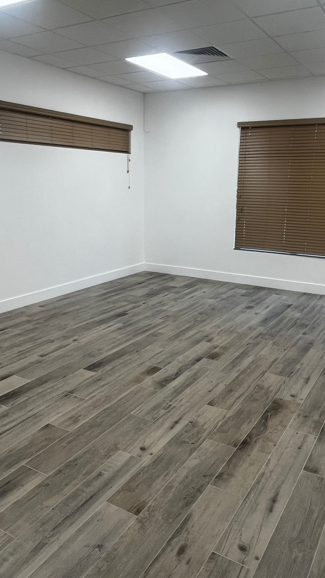 Event room empty — corner with wood-look flooring and brown window blinds