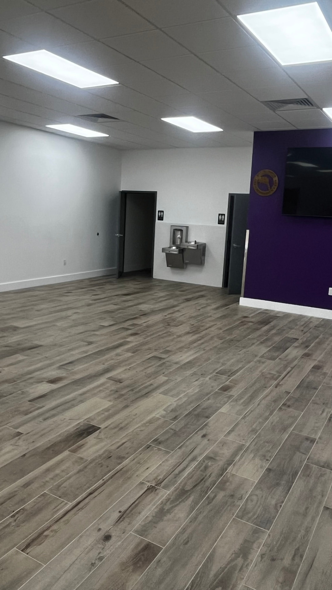 Main hall empty — purple accent wall, mounted screen and water fountain